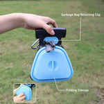 Blue pet waste bag scooper with a hand holding it, set against a grassy background.
